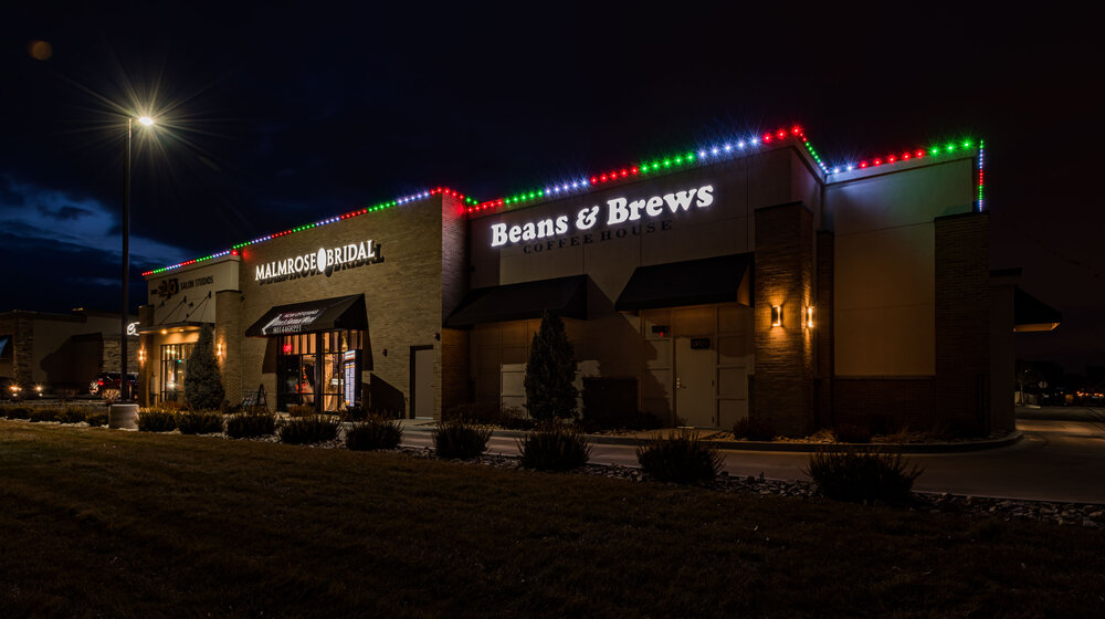 Red and green holiday lighting on a commercial roofline