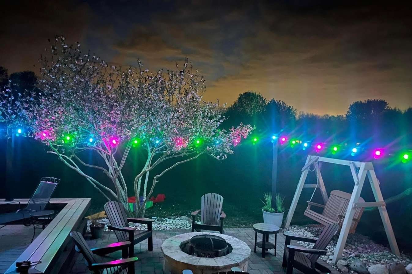 Backyard firepit beneath multicolor globe lighting