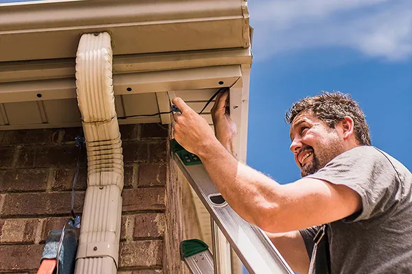 Installer fitting permanent lighting to residential fascia