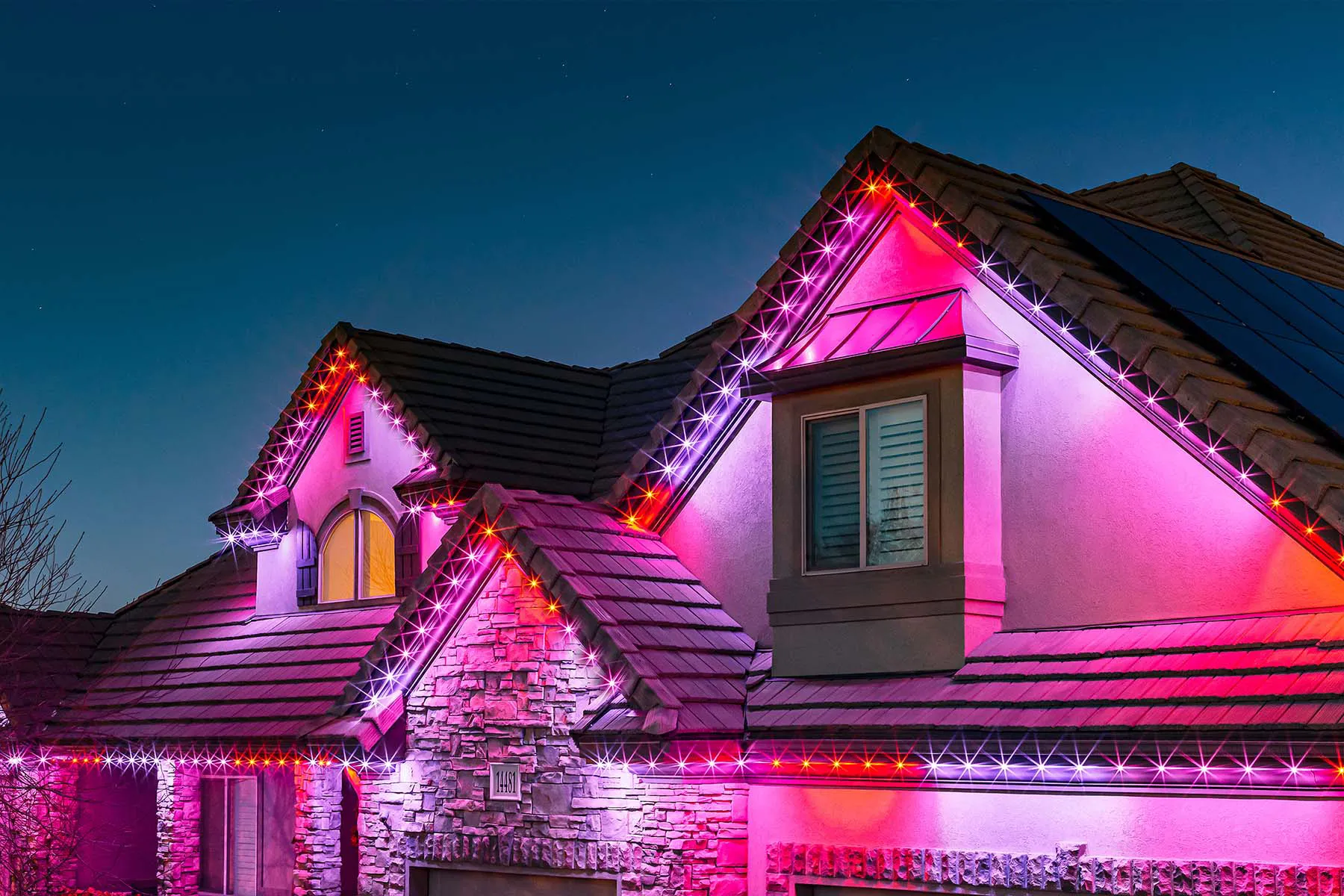 Residential home with magenta holiday roofline lighting
