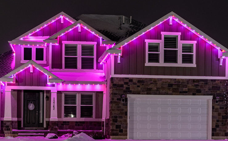 Pink permanent lighting outlining a home's roof peaks